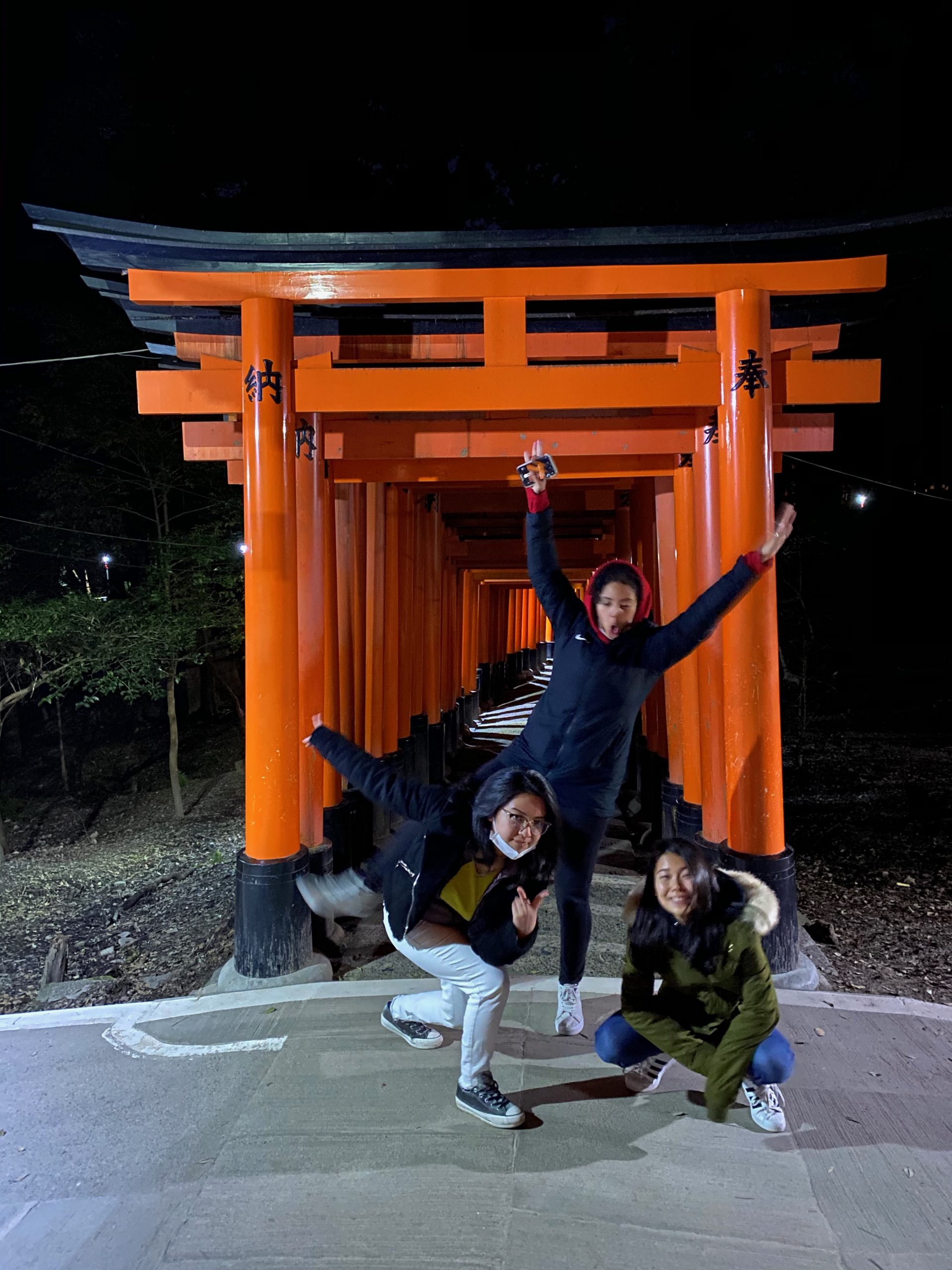 Isis, Emi, and Marina doing a silly pose in front of orange and black arches