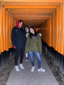 Three female students standing in an orange tunnel. 