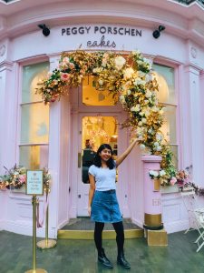 Peggy Porschen cake and tea house with lots of flowers decorating the door.  Girl posing in front.
