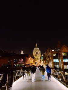 People walking on the tower bridge with St. Paul's in the background.