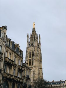 Stone church with tower topped with a golden spire in Bordeaux, France.