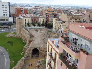 Showing a view of the city of Tarragona. Taken from the top of a Roman circus. There are ruins in the foreground and modern buildings in the background. 