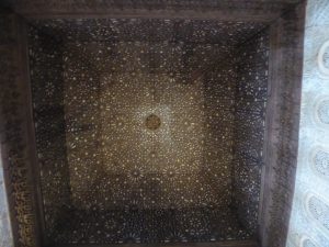 A square ceiling from the underside. Little yellow dots provide beautiful contrast with the brown of the ceiling.