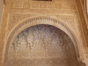 A clay-colored and speckled pattern on an arched wall of La Alhambra