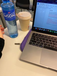A laptop, coffee cup, and water bottle on a classroom desk