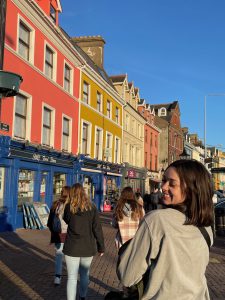 Students walking down the street in front of colorful row houses and shops in Cork, Ireland.